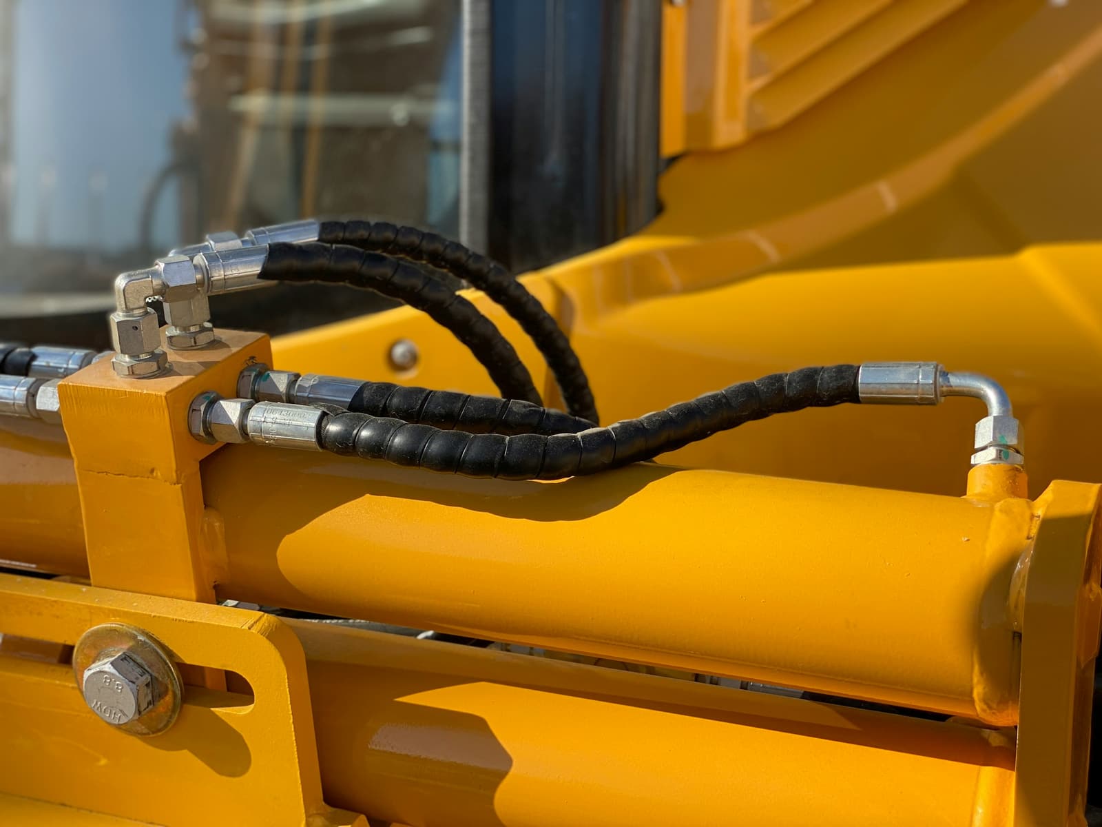 A yellow hydraulic cylinder with its hoses connected