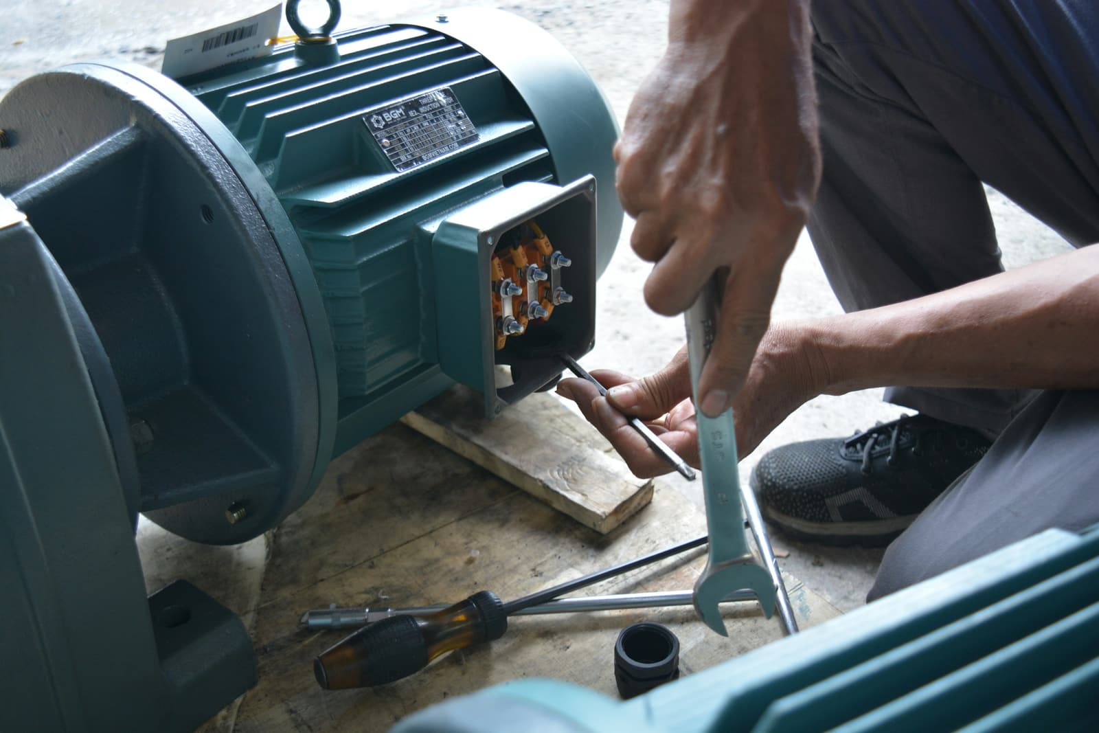 A technician wiring the terminal box of an electric motor