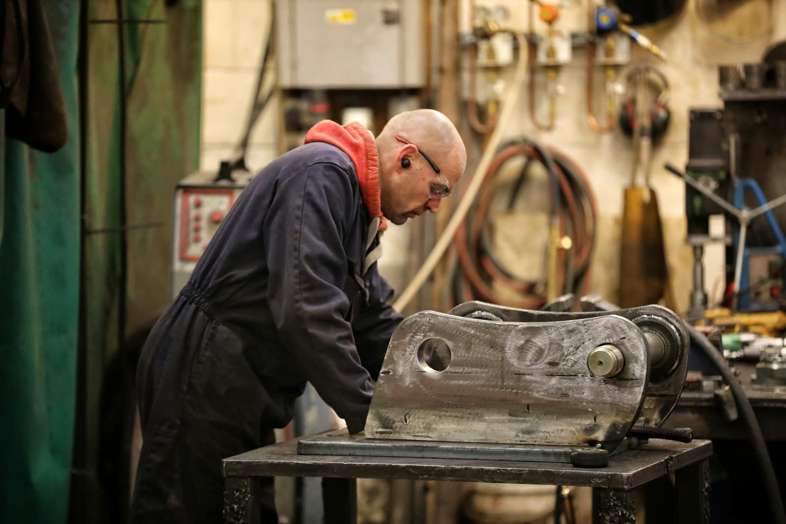 A technician leaning over a heavy steel part on the rebuild bench